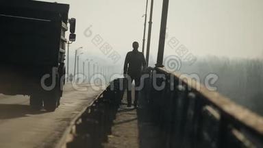 在桥上行走的年轻人.. 汽车在路上行驶。 早晨和雾。 春天。